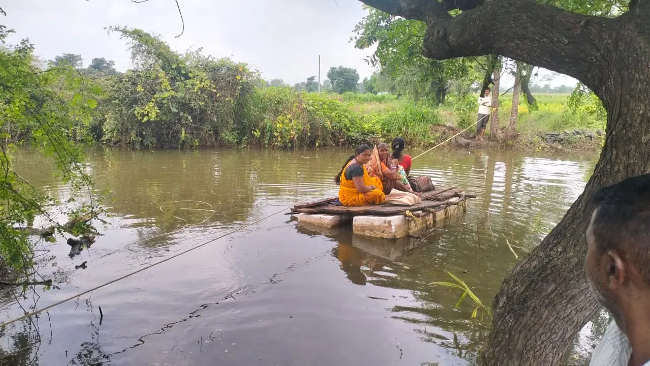शेतकरी पाण्यातून शेताकडे जाताना दिसत असलेला फोटो (धोकादायक परिस्थिती दर्शवणारा).