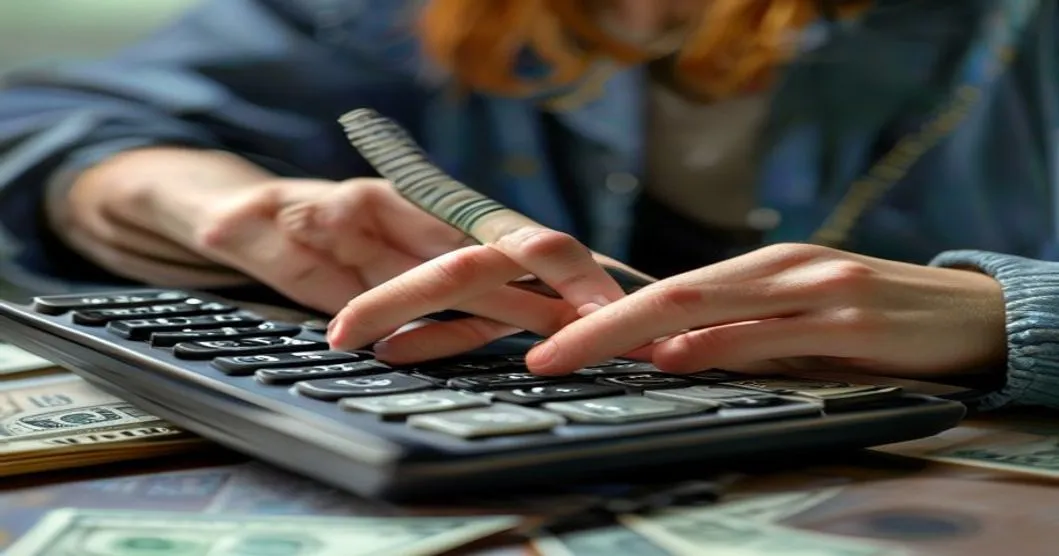 कॅल्क्युलेटरवर पैसे मोजत असलेल्या व्यक्तीची प्रतिमा